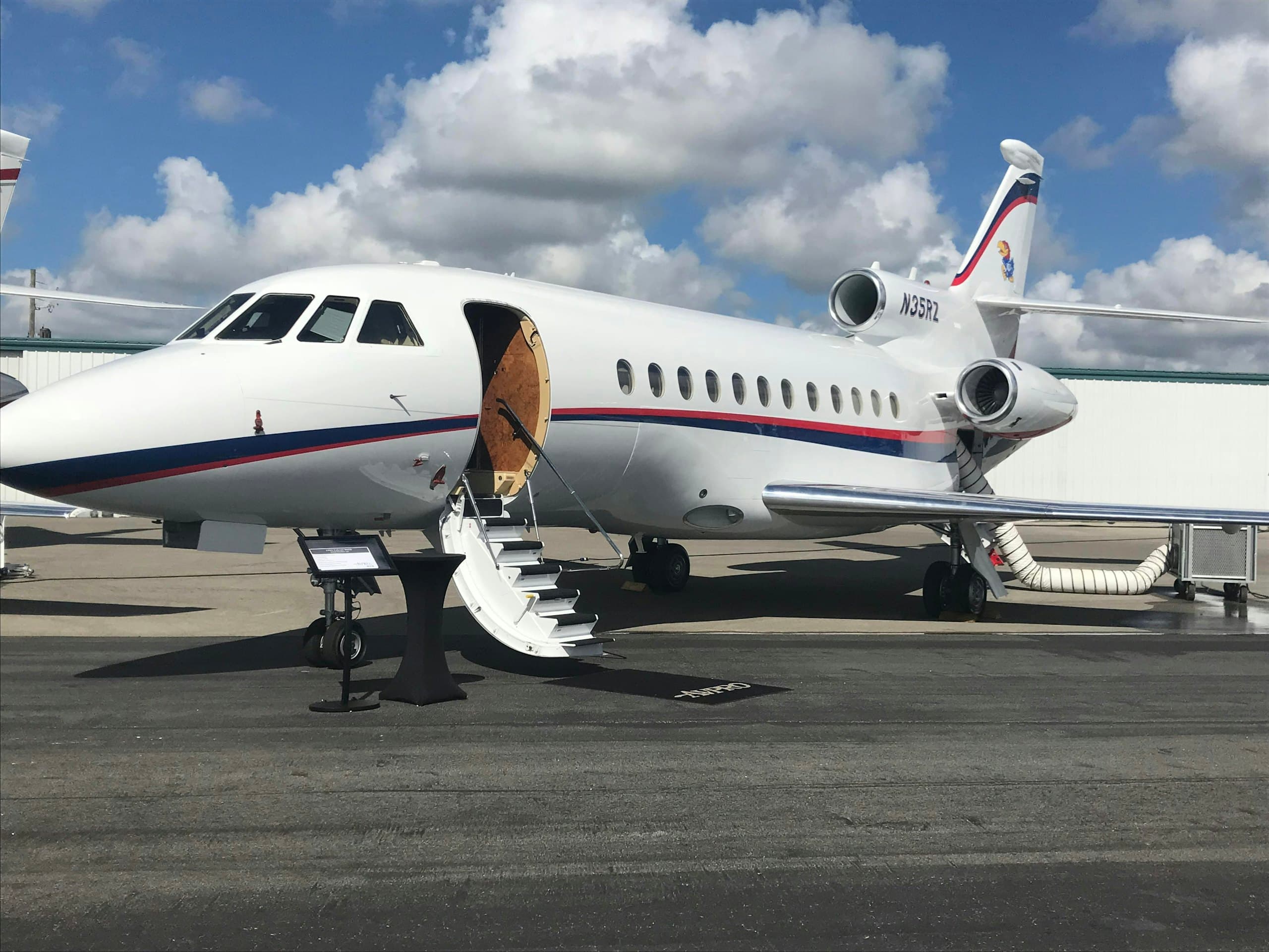 Business jet parked on the ramp with its airstair down, three-quarter view in daylight